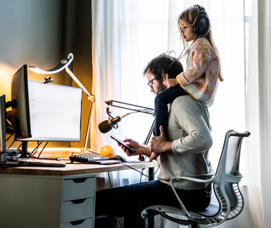 Man working from home on computer with daughter on his shoulders.