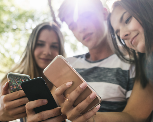 Three young people looking at there cell phones together