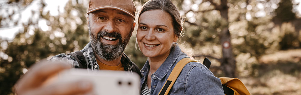 A man and a woman in the woods taking a selfie